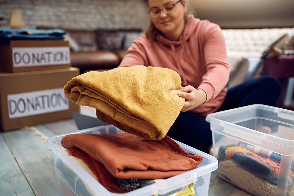 Close-up of woman sorting clothes while packing donation boxes f